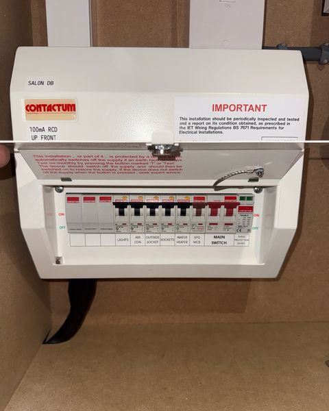 Example: a consumer unit with its cover open, every breaker and label visible, photographed from a step back